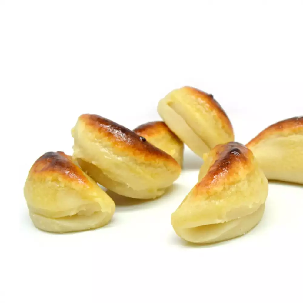 Varias piezas de mazapán con forma de media luna o lágrima, algunas con un ligero dorado en la parte superior, dispuestas sobre un fondo blanco