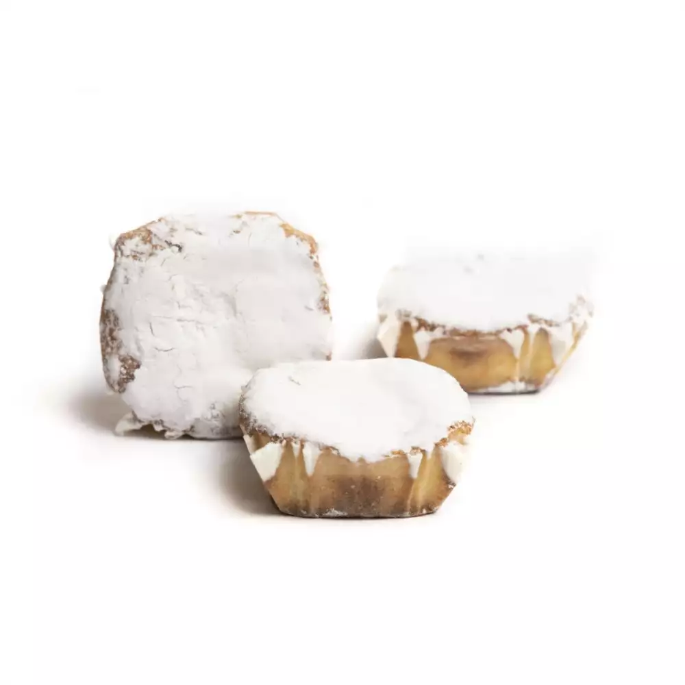 Tres dulces individuales con forma irregular o ligeramente cuadrada, cubiertos con una gruesa capa de glaseado blanco o azúcar glas que les da un aspecto nevado.