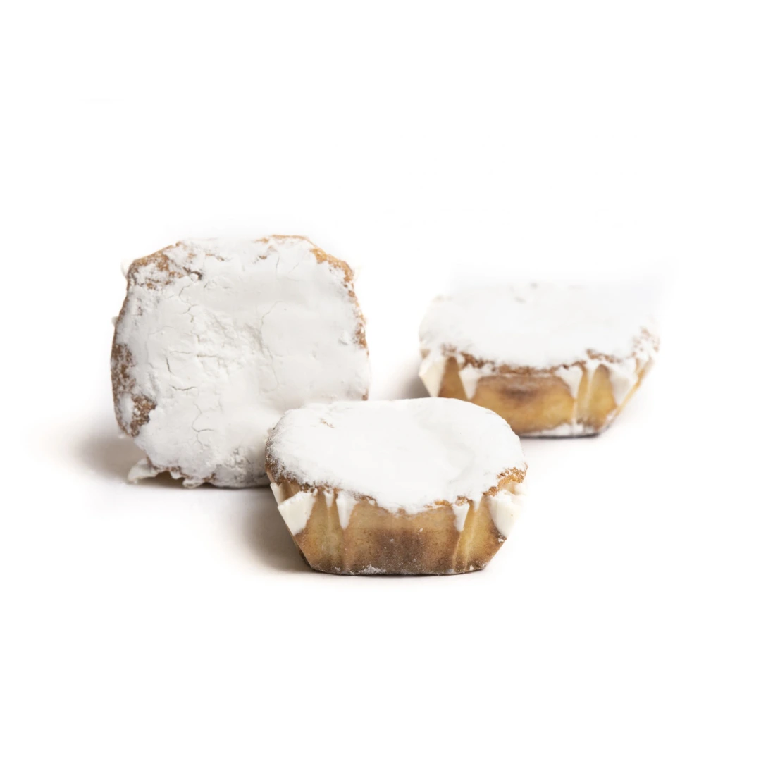marquesitas-de-mazapan Tres dulces individuales con forma irregular o ligeramente cuadrada, cubiertos con una gruesa capa de glaseado blanco o azúcar glas que les da un aspecto nevado.